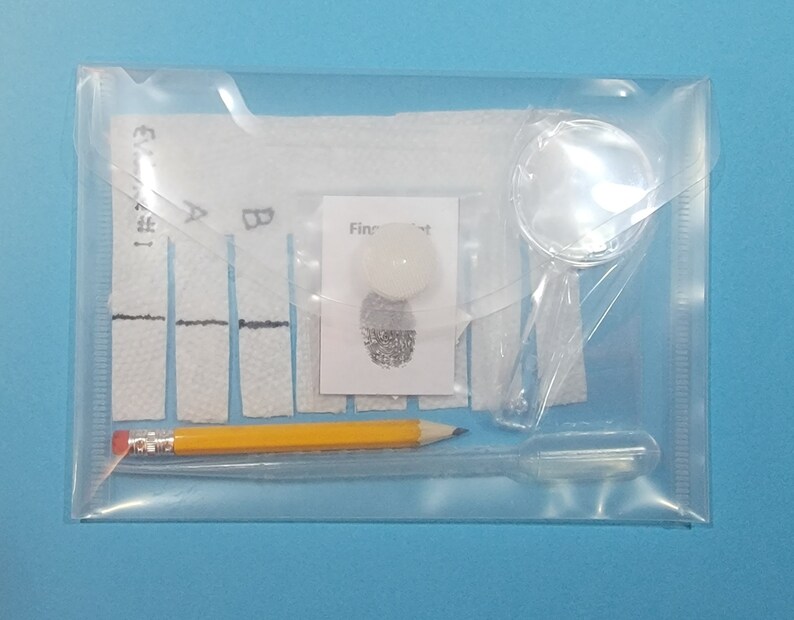 May include: A clear plastic envelope containing a fingerprint kit. The kit includes a magnifying glass, a pencil, a small white card with a fingerprint on it, and a sheet of paper with labeled sections for testing.