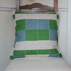 May include: A green and blue patterned cushion with a linen fabric cover.