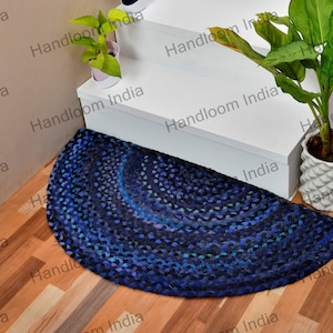 Può includere: Un tappeto in juta blu e viola a mezzo cerchio con un design intrecciato. Il tappeto è posizionato in fondo a una serie di scale bianche.