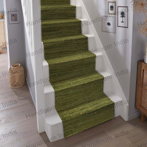 May include: Green jute stair treads with a woven texture. The treads are placed on a set of stairs with white risers and a white handrail.