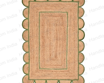 May include: A rectangular jute rug with a scalloped border and a green trim. The rug has a woven pattern and is made of natural fibers.