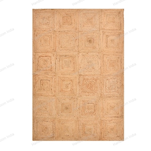 May include: A rectangular jute rug with a repeating square pattern. The rug is a natural tan color, with each square featuring a concentric design. The texture appears woven, suitable for a living room or bedroom.