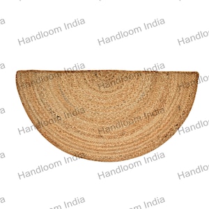 May include: A half-circle jute rug with a natural brown color. The rug is made of woven jute fibers and has a slightly textured surface.