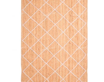 Puede incluir: Una alfombra rectangular de yute con un diseño de rombos. La alfombra tiene un color marrón natural con un diseño de rejilla de rombos blancos. La alfombra está hecha de fibras de yute tejidas, creando una superficie texturizada.
