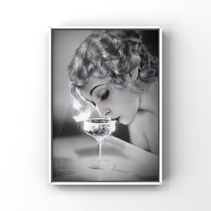 Op de afbeelding: Een zwart-witfoto van een vrouw met kort, golvend haar, die naar een glas champagne kijkt.
