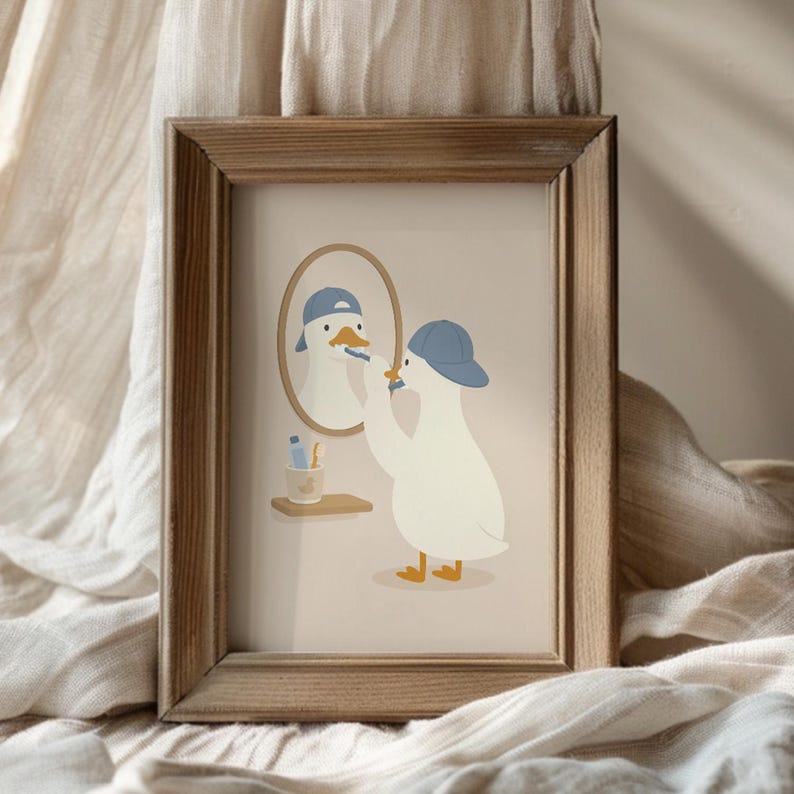 May include: A framed art print featuring a white duck wearing a blue baseball cap, brushing its teeth in front of an oval mirror. A small shelf holds a toothbrush and toothpaste. The illustration uses a soft color palette on a light background.