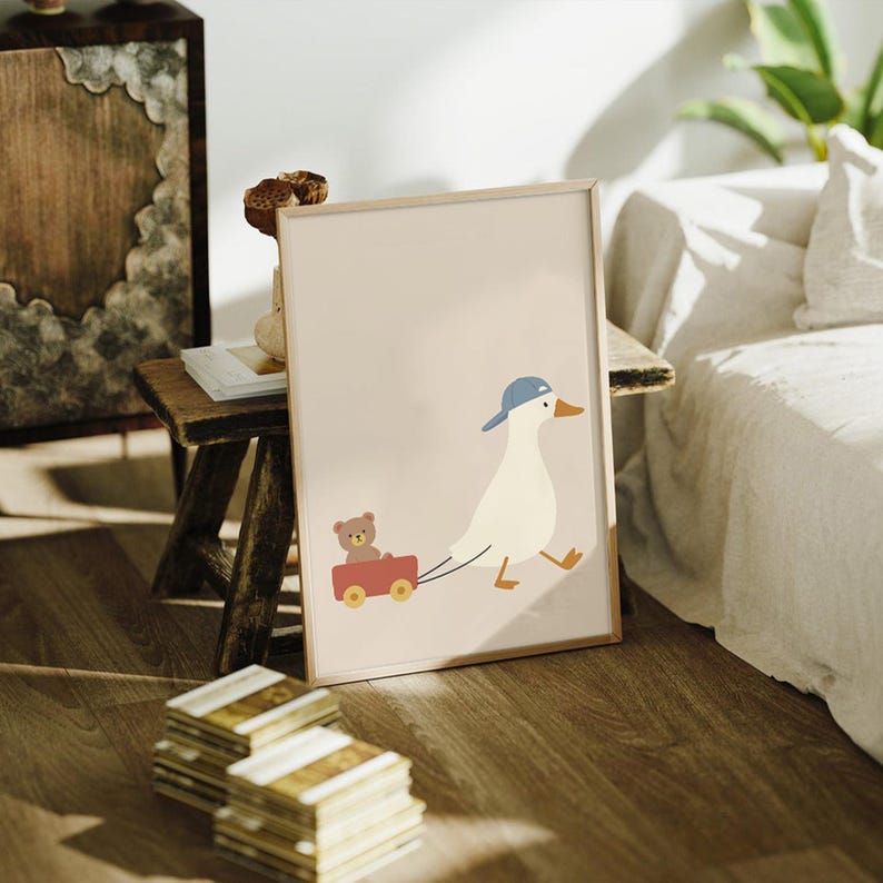 Pode incluir: Impress&atilde;o emoldurada com uma ilustra&ccedil;&atilde;o de um pato de desenho animado com bon&eacute; azul puxando uma carro&ccedil;a vermelha com um ursinho de pel&uacute;cia. A obra tem um fundo bege claro e uma moldura de madeira, ideal para um quarto infantil.
