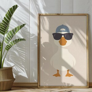 May include: A framed art print featuring a cartoon duck wearing a blue baseball cap and black sunglasses. The duck has an orange beak and feet, set against a beige background. The artwork is in a wooden frame.