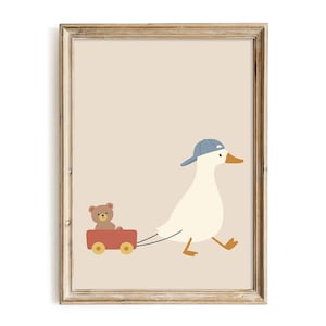 Pode incluir: Uma impress&atilde;o emoldurada com uma ilustra&ccedil;&atilde;o de um pato branco com bon&eacute; azul, puxando uma carro&ccedil;a vermelha com um ursinho de pel&uacute;cia. A obra de arte tem um fundo neutro e uma moldura de madeira r&uacute;stica.