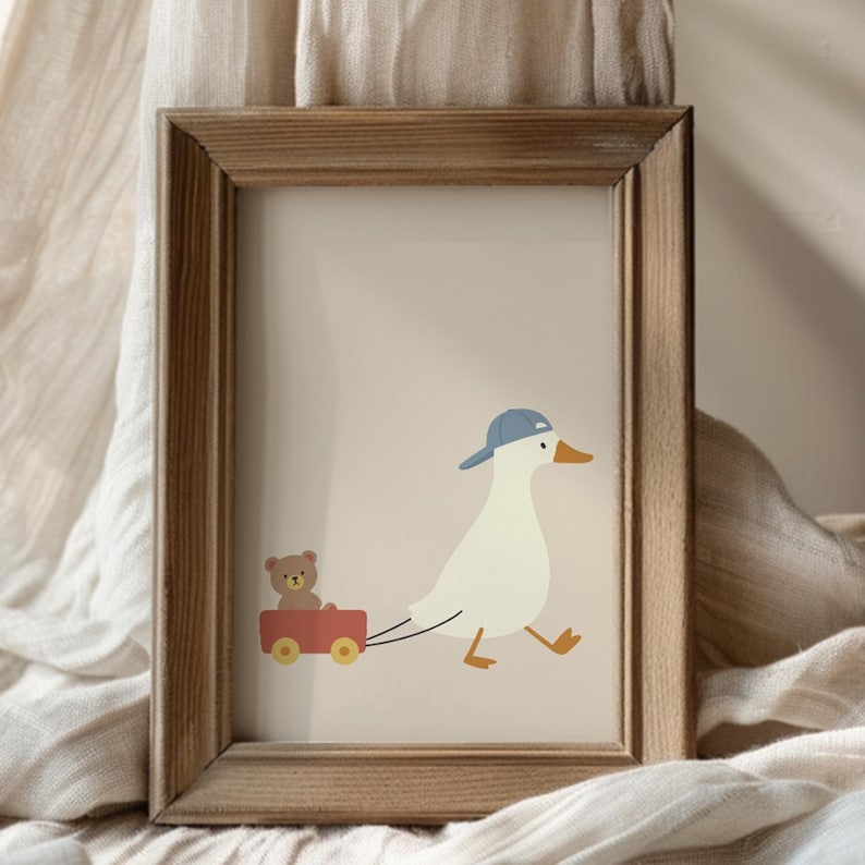 Pode incluir: Impress&atilde;o emoldurada com um ganso de desenho animado usando um bon&eacute; de beisebol azul, puxando uma carro&ccedil;a vermelha com um ursinho de pel&uacute;cia dentro. O ganso tem p&eacute;s e bico laranja. A obra de arte est&aacute; em um fundo neutro.