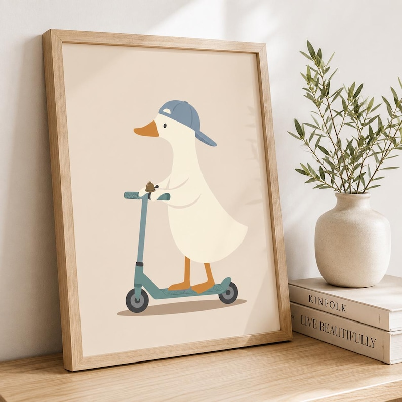 May include: A framed wall art print featuring a cream-colored duck wearing a blue baseball cap and riding a teal kick scooter. The illustration is set against a solid light beige background, showcasing clean lines and a simple, flat graphic design.