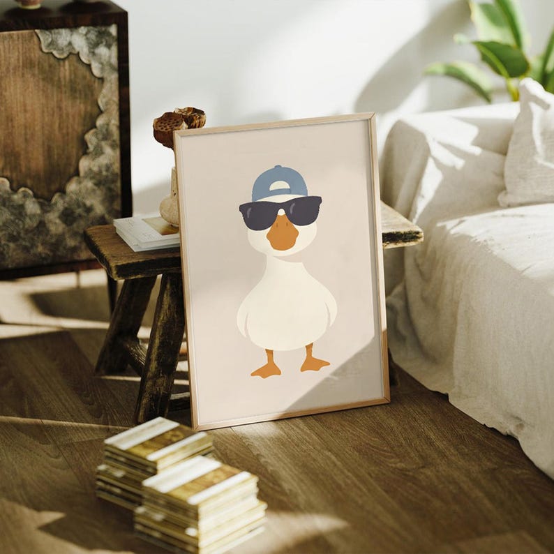 May include: Framed art print featuring a cartoon duck wearing sunglasses and a blue baseball cap. The duck has an orange beak and feet, set against a neutral background. The artwork is in a wooden frame.