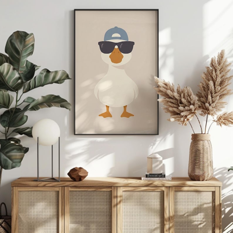 May include: Framed art print featuring a cartoon goose wearing sunglasses and a blue baseball cap. The goose is white with orange feet and beak, set against a neutral background. The artwork is in a black frame.