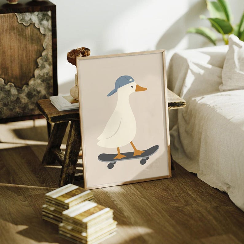 May include: A framed art print featuring a cartoon duck wearing a blue baseball cap and riding a skateboard. The duck is white with an orange beak and feet. The background is a light beige color.