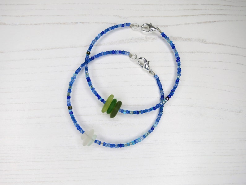 Dainty bracelet with three pieces of Cornish sea glass surrounded by tiny blue glass beads and fastened with a silver plated lobster catch, in a choice of white or green shades of glass.