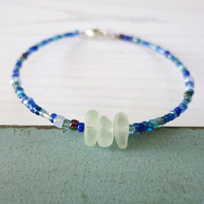 Dainty bracelet with three pieces of Cornish sea glass surrounded by tiny blue glass beads and fastened with a silver plated lobster catch.