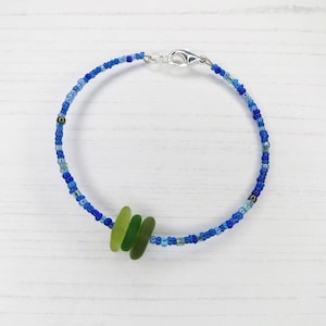 Dainty bracelet with three pieces of Cornish sea glass in shades of green surrounded by tiny blue glass beads and fastened with a silver plated lobster catch.