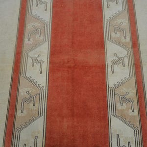 May include: A close-up view of a rug with a repeating pattern. The rug features vertical stripes in cream, coral, and a darker coral. The cream stripes have a repeating geometric design in a darker color.