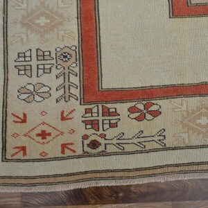 May include: Close-up of a beige and rust-colored rug with intricate geometric patterns. The rug features a border with repeating floral and geometric motifs in shades of rust, beige, and brown. The rug's design is a traditional style.