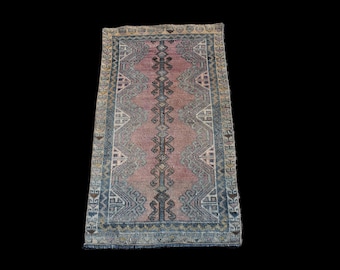 May include: A vintage pink and blue rug with a geometric pattern. The rug has a fringed edge and is made of wool.