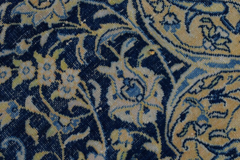 K&ouml;nnte beinhalten: Nahaufnahme eines Abschnitts eines persischen Teppichs mit detailliertem Blumenmuster. Der Teppich hat einen dunkelblauen Hintergrund mit cremefarbenen, hellblauen und gelben Blumen- und Rankenmotiven. Das Design ist aufwendig und traditionell und zeigt einen klassischen Teppichstil.