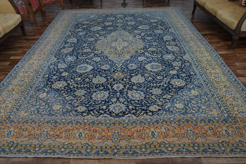 K&ouml;nnte beinhalten: Gro&szlig;er, rechteckiger Teppich mit einem komplizierten Blumenmuster in Marineblau, Creme und Orange. Der Teppich hat ein zentrales Medaillon-Design und einen detaillierten Rand. Der Teppich liegt auf einem Holzboden.