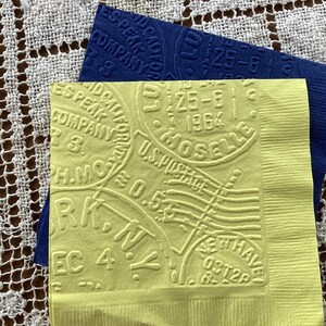 May include: Two embossed paper napkins. One is yellow with text including "U.S. POSTAGE" and "NEW HAVEN". The other is dark blue with text including "ESPEAK COMPANY". Both have a vintage aesthetic.