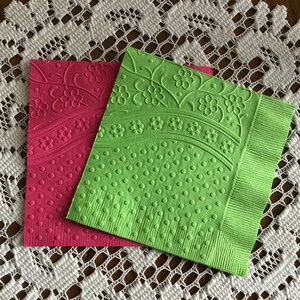 May include: Two square paper napkins, one pink and one green, with embossed floral and polka dot patterns.