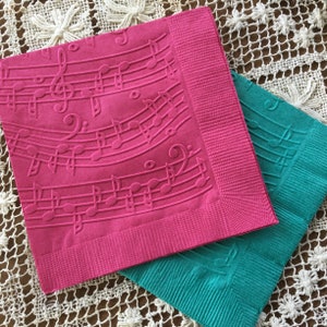 May include: Two paper napkins with an embossed musical note design. One napkin is pink and the other is teal.