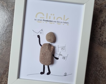 May include: A white framed picture with a black and white drawing of a person holding a letter. The drawing is made with stones. The text in the picture reads "Glück ist einen Postboten wie Sie zu haben."