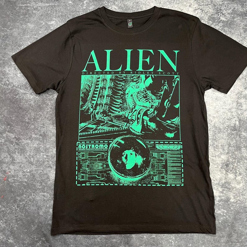 May include: Black t-shirt with a green graphic print of the Alien movie poster. The graphic includes the title "Alien", "Directed by Ridley Scott", and a scene from the movie.