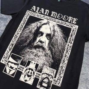 Puede incluir: Camiseta negra con un estampado gráfico blanco de Alan Moore, el autor de Watchmen y V de Vendetta. El gráfico también incluye imágenes de Rorschach, Ozymandias y el Comediante.