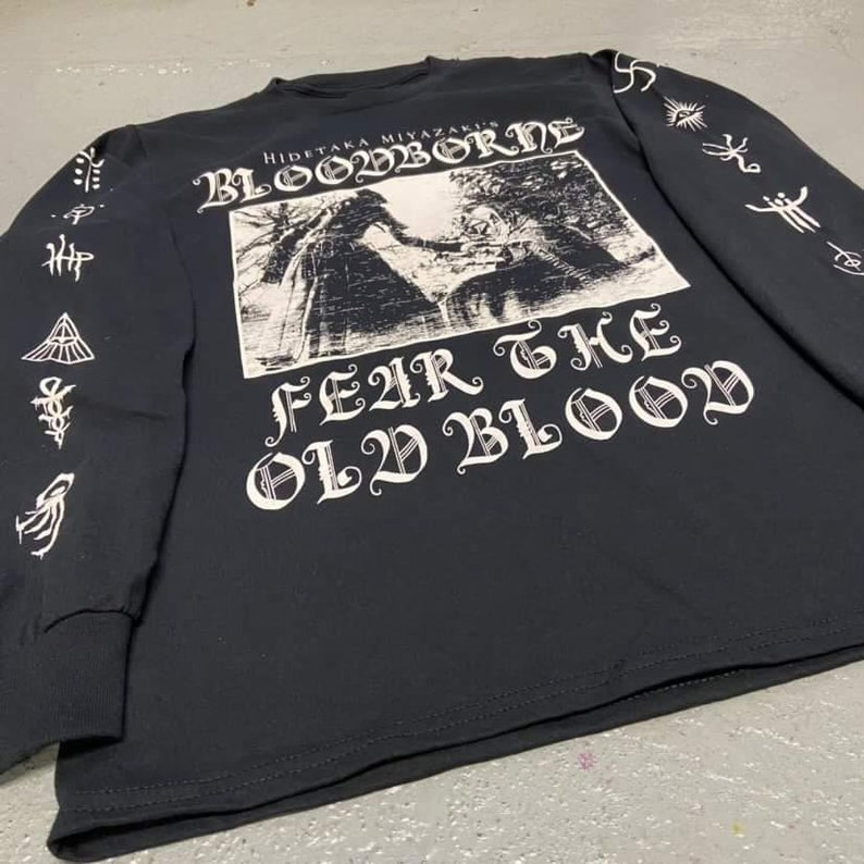 May include: Black long-sleeve shirt with a white graphic print of a scene from the video game Bloodborne. The text "Fear the Old Blood" is printed in a gothic font.