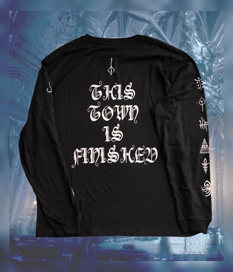 May include: Black long-sleeve shirt with white text that reads "THIS TOWN IS FINSICHED" and white graphic designs on the sleeves.