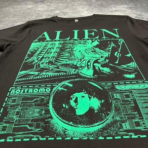 May include: Black t-shirt with a green graphic print of the alien from the movie Alien. The graphic includes the text "Alien", "Directed by Ridley Scott", "USCSS Nostromo", and "Weyland-Yutani Corporation".