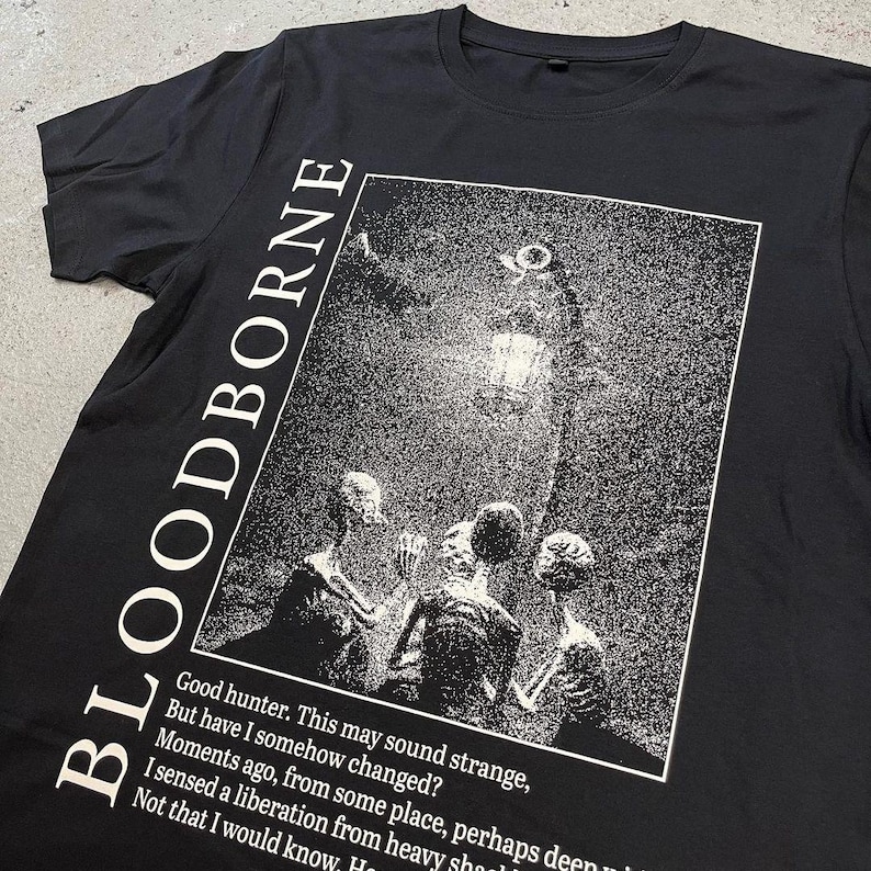 May include: Black t-shirt with a white graphic print of a scene from the video game Bloodborne. The text "Good hunter. This may sound strange, But have I somehow changed? Moments ago, from some place, perhaps deep I sensed a liberation from heavy shoulders. Not that I would know. How" is printed below the graphic.