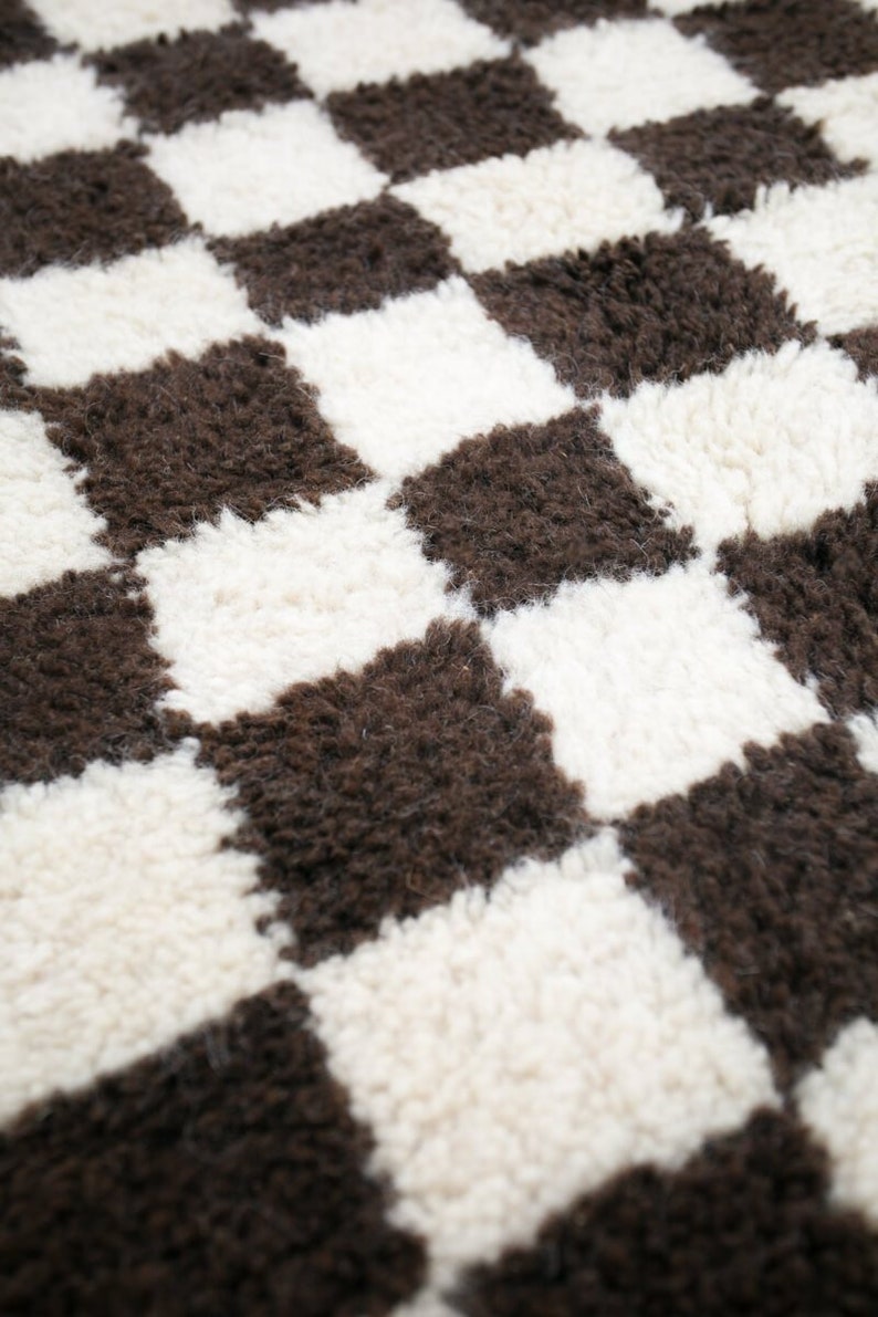 May include: A close-up of a brown and white checkered rug with a fluffy texture.