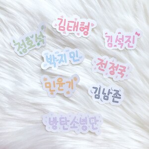 May include: A set of nine colorful stickers with Korean text. The stickers feature various phrases, including "Kim Taehyung", "Jeon Jungkook", "Park Jimin", and "Min Yoongi".