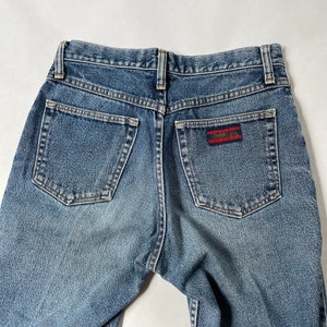 May include: A pair of blue denim jeans with a red and black patch on the back pocket that says "Twenty 8 12".