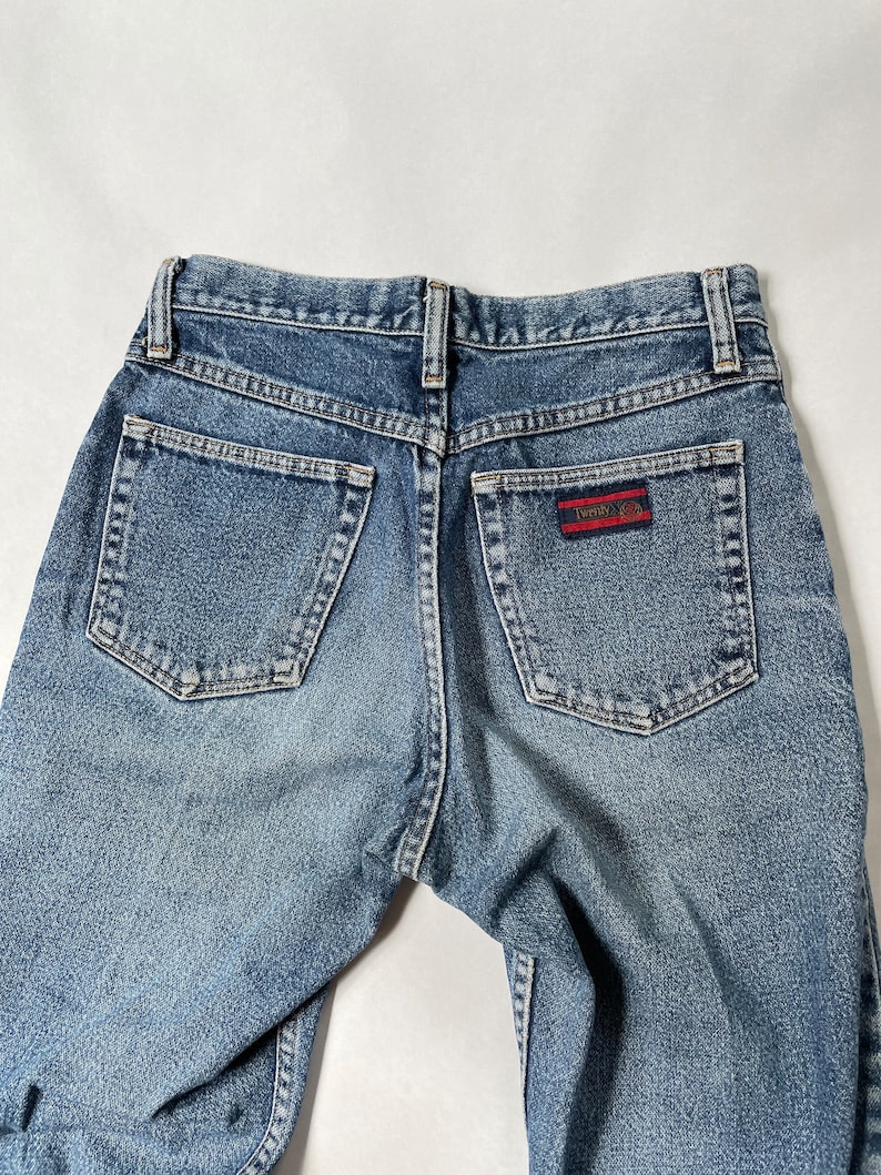 May include: A pair of blue denim jeans with a red and black patch on the back pocket that says "Twenty 8 12".