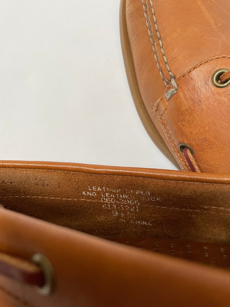 May include: Close-up of the inside of a brown leather shoe. The shoe is labelled "Leather Upper and Leather Sock" and "9 1/2" in size. The shoe was made in China.