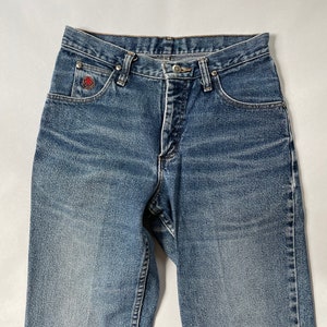 May include: A pair of light blue denim jeans with a red logo on the left pocket.