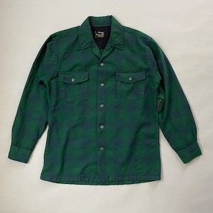 Pode incluir: Uma camisa de botões de manga comprida em xadrez verde e preto com dois bolsos no peito e gola.