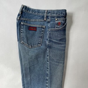 May include: A pair of blue denim jeans with a red and white logo patch on the back pocket.