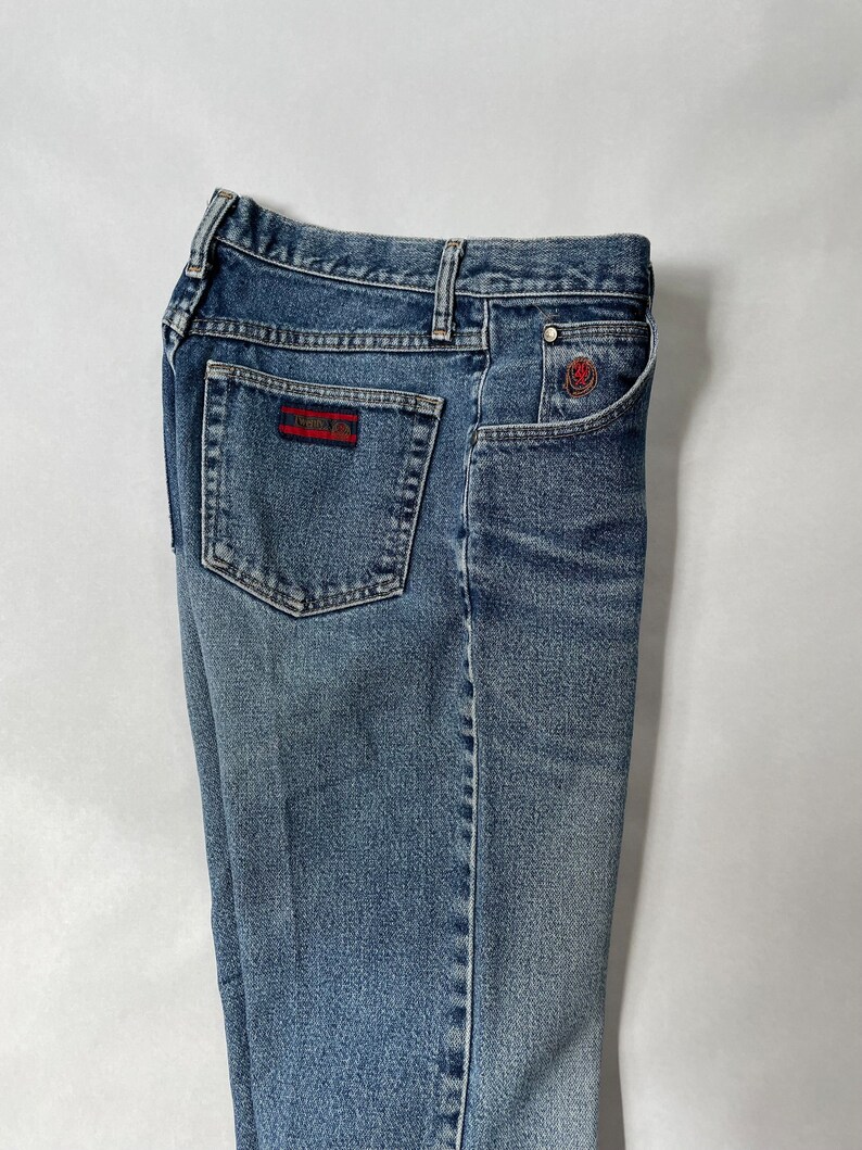 May include: A pair of blue denim jeans with a red and white logo patch on the back pocket.