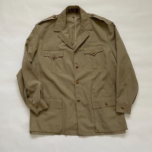 May include: Tan safari jacket with four front pockets and button closures. The jacket has a collared neckline and epaulets on the shoulders. The long-sleeved jacket is made of a lightweight material.