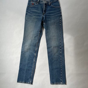 May include: A pair of blue denim jeans with a button fly and a red logo on the back pocket.