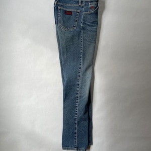 May include: A pair of blue denim jeans with a red and black patch on the back pocket.
