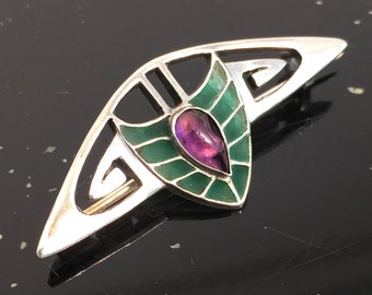May include: A silver and green enamel brooch with a purple gemstone in the center. The brooch is in the shape of a stylized leaf.