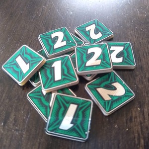 May include: A pile of green and white square tiles with the numbers 1 and 2 printed on them.